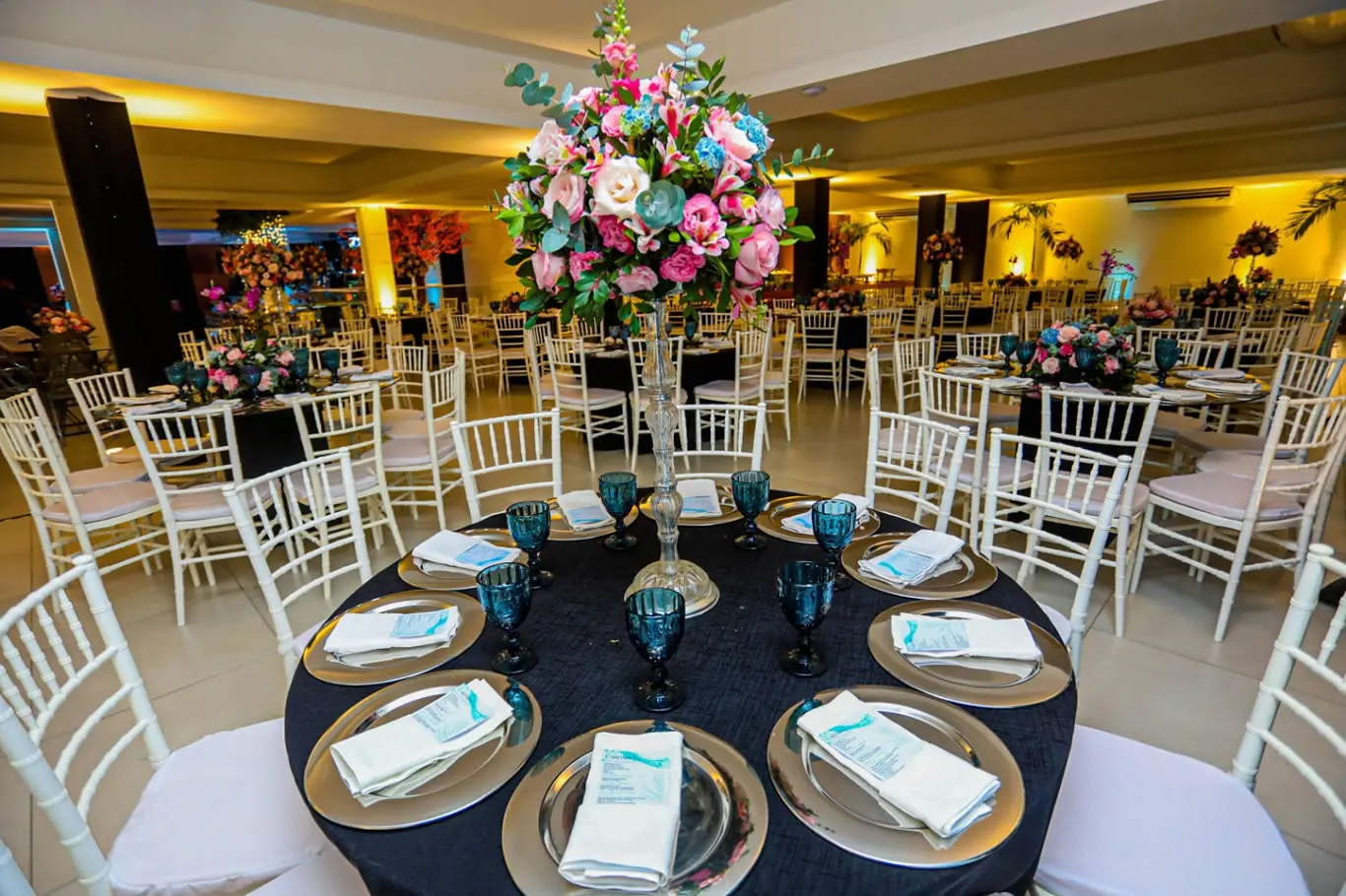 Salão do Espaço CDL Festas decorado, com mesas e cadeiras Tiffany